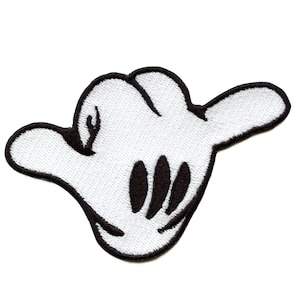 Puede incluir: Mano de fieltro blanco con costuras negras, haciendo un signo shaka, un gesto hawaiano de paz y buenas vibraciones.