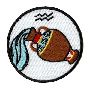 Puede incluir: Parche bordado con el símbolo astrológico de Acuario, una jarra de agua que vierte agua, con el símbolo del agua encima. El parche es circular y tiene un fondo blanco con un borde negro.