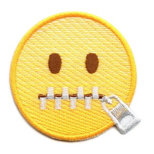 May include: Yellow embroidered emoji face with a zipper across the mouth. The zipper is white with a silver zipper pull.