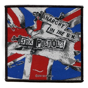 Puede incluir: Un parche en blanco y negro con un diseño de bandera Union Jack. Las palabras "Sex Pistols" y "Anarchy in the U.K." están impresas en el parche. El parche tiene un borde negro.