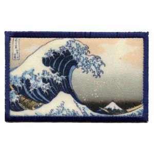 Könnte beinhalten: Ein blauer und weißer gestickter Aufnäher mit einer großen Welle und dem Berg Fuji im Hintergrund. Die Welle ist ein traditionelles japanisches Design.