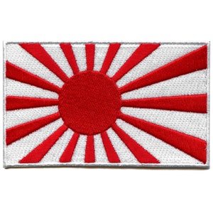 May include: A red and white embroidered patch depicting the Rising Sun Flag of Japan. The flag features a large red circle in the center, representing the sun, with 16 red rays extending outwards.