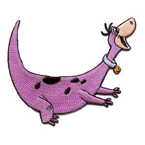 Puede incluir: Un parche bordado de Dino, el dinosaurio morado de la serie de dibujos animados Los Picapiedra. Dino lleva un collar con una campana y tiene una expresión feliz en su rostro.