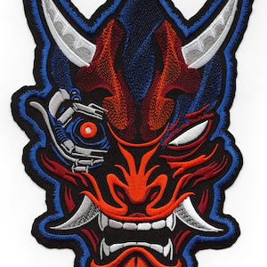 May include: Embroidered patch featuring a red and blue oni mask with a mechanical eye. The mask has sharp teeth and horns, and is outlined in blue.