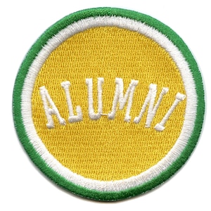 May include: A yellow circle with a white border and a green outer border. The word "ALUMNI" is embroidered in white on the yellow circle.