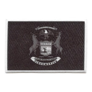 Pode incluir: Um remendo bordado em preto e branco com o selo do estado de Michigan. O selo representa uma águia careca com as asas abertas, um escudo com a palavra "TUEBOR" e dois alces. O texto "SI QUAERIS PENINSULAM AMOENAM CIRCUMSPICE" está escrito em uma faixa abaixo do escudo.