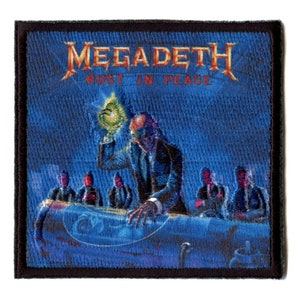 Pode incluir: Um remendo bordado azul e preto com o nome da banda "Megadeth" e o título do álbum "Rust in Peace" em letras vermelhas. A imagem mostra um homem de terno segurando um orbe brilhante, cercado por outras figuras de terno.