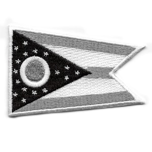 Può includere: Una toppa ricamata in bianco e nero della bandiera dello stato dell'Ohio. La bandiera presenta un cerchio bianco con un cerchio più piccolo all'interno, circondato da 17 stelle bianche su uno sfondo triangolare nero. La bandiera è bordata da tre strisce bianche.