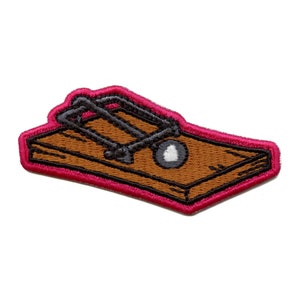 Puede incluir: Parche bordado con un diseño de ratonera de estilo caricatura. El parche tiene una base de madera marrón, un mecanismo de resorte de metal negro y un cebo blanco y gris. Está delineado con un borde rosa brillante.