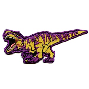 May include: Purple and yellow embroidered iron-on patch of a dinosaur with an open mouth.