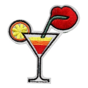 Könnte beinhalten: Gestickter Bügelaufkleber mit einem Cocktailglas mit einem roten Lippenstrohhalm, einer Orangenscheibe und einer geschichteten gelben, orangen und roten Flüssigkeit.
