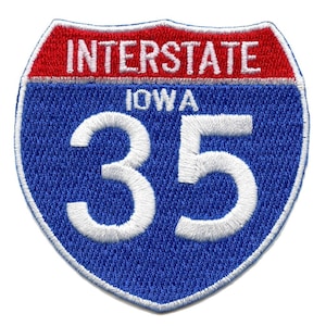 Puede incluir: Una señal de carretera interestatal azul y roja con el número 35 y el nombre del estado "Iowa" en texto blanco.
