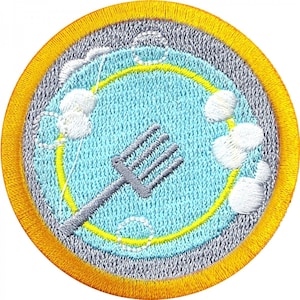 May include: A blue and yellow embroidered patch with a fork and white flowers. The patch has a gray background and a yellow border.