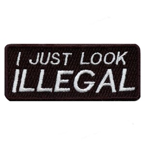 May include: Black embroidered patch with white text that reads "I just look illegal".