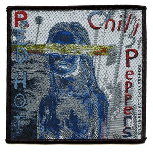 Może przedstawiać: Tkana naszywka Red Hot Chili Peppers z twarzą kobiety częściowo zasłoniętą czerwono-żółto-niebieskim paskiem. Tekst "Red Hot Chili Peppers" znajduje się po lewej i prawej stronie naszywki.