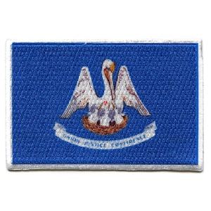 May include: A blue embroidered patch with the state seal of Louisiana. The seal features a white pelican with a red spot on its chest, feeding its young in a nest. The text "Union Justice Confidence" is written on a white scroll below the pelican.
