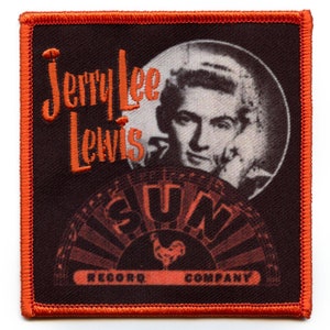 May include: A black and orange embroidered patch featuring the text "Jerry Lee Lewis" and "SUN RECORD COMPANY" with a black and white image of Jerry Lee Lewis in the background.