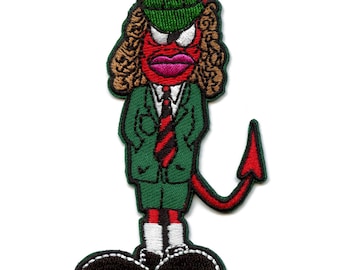 Op de afbeelding: Rood duivel-tekenfilmfiguur met een groen pak, een rood-zwarte gestreepte stropdas en een groene hoed met een wit symbool. Het personage heeft een rode staart en zwarte schoenen.