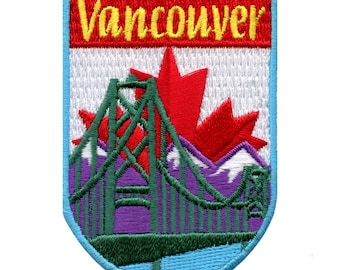May include: An embroidered patch with a blue, white, and red shield shape. The shield has a red maple leaf, a green bridge, and the word "Vancouver" in yellow letters.