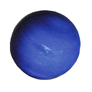 May include: A round, blue fabric object with a textured surface. The color transitions from a deep blue at the edges to a lighter shade in the center. The object is set against a white background.