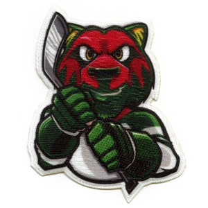 May include: Embroidered patch featuring a bear mascot in green, red, and white, holding a hockey stick. The bear has an angry expression and is wearing a hockey uniform. The patch has a white border and is likely for apparel or accessories.