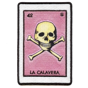 May include: A pink and white embroidered patch with a yellow skull and crossbones. The patch has the number 42 and the text "LA CALAVERA" on it.