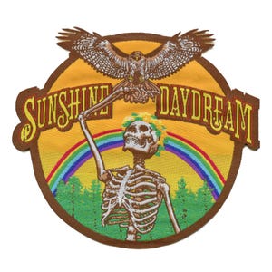 May include: A brown embroidered patch with a skeleton holding a hawk in its talons. The patch has a yellow background with a rainbow and the text "Sunshine Daydream".