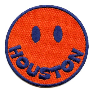 May include: Orange and blue embroidered smiley face patch with the word "HOUSTON" around the edge.