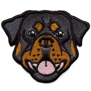 May include: Embroidered patch featuring a Rottweiler dog's face. The patch has a black and brown color scheme with detailed stitching. The dog's mouth is open, revealing a pink tongue and white teeth. The patch is designed to be ironed on or sewn.