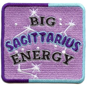 Puede incluir: Parche bordado morado y azul con estrellas blancas y el texto "BIG SAGITTARIUS ENERGY" en letras negras y grises.