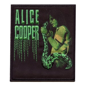 Könnte beinhalten: Grüner gestickter Aufnäher mit dem Text "Alice Cooper" und einem grünen Bild einer Person, die eine Schlange hält.