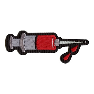 May include: A red and gray embroidered iron-on patch of a syringe with a drop of blood dripping from the needle.