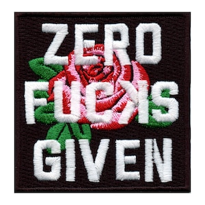 Op de afbeelding: Vierkantig geborduurd embleem met de witte tekst "ZERO FUCKS GIVEN" over een rode en roze roos met groene bladeren, op een donkerbruine achtergrond. Geschikt voor kleding of accessoires.