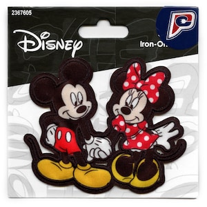 May include: Iron-on patch featuring Mickey Mouse and Minnie Mouse. Mickey is wearing red shorts and yellow shoes. Minnie is wearing a red dress with white polka dots and a red bow with white polka dots. The patch is on a white background with the word "Disney" printed in black.