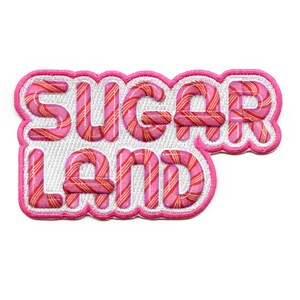Peut inclure: Patch brodé rose et blanc avec le texte "Sugar Land" dans un motif de canne à sucre.