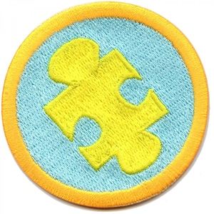 May include: A yellow jigsaw piece on a light blue background with a bright orange border. The jigsaw piece is a symbol of autism awareness.
