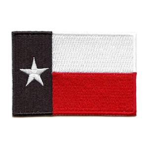 Puede incluir: Un parche de la bandera del estado de Texas. El parche está hecho de tela y tiene una estrella blanca sobre un fondo negro, con una franja roja debajo de una franja blanca.