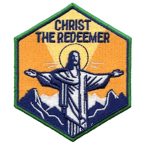 Puede incluir: Parche bordado con una representación de Jesucristo con los brazos extendidos, de pie en la cima de una montaña con un halo sobre su cabeza. El fondo es una puesta de sol con un cielo amarillo y montañas azules. El texto "CHRIST THE REDEEMER" está sobre la imagen.