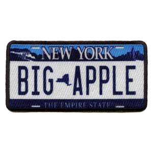 May include: A blue and white embroidered patch with the text "NEW YORK" and "BIG APPLE" with a silhouette of the state of New York in between the words. The text "THE EMPIRE STATE" is at the bottom of the patch.