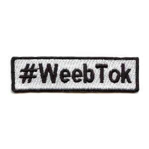 May include: A white rectangular embroidered patch with black stitching. The patch says "#WeebTok" in black.