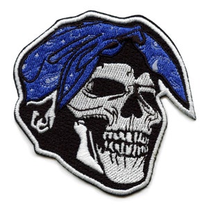 May include: Embroidered patch featuring a white skull wearing a blue bandana with white stars. The skull has a black background and is outlined in white.