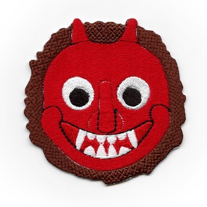 Puede incluir: Parche bordado rojo y blanco de una cara de demonio de dibujos animados con cuernos, ojos grandes y una amplia sonrisa.