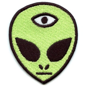 May include: Green alien face with a third eye in the center of the forehead. The alien has black eyes and a serious expression.