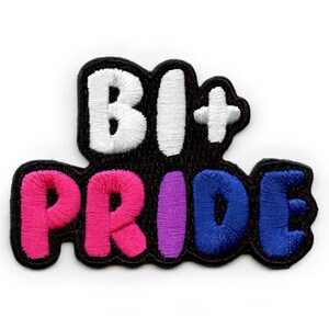 May include: Embroidered patch with the text "Bi+ Pride" in white, pink, purple, and blue lettering on a black background.