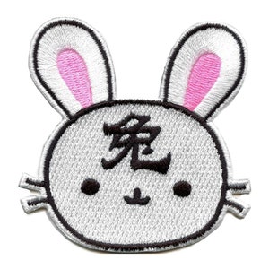Puede incluir: Parche de conejo blanco bordado con orejas rosas y el carácter japonés para "fantasma" en negro.