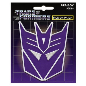 Pode incluir: Etiqueta para passar a ferro com o logotipo dos Transformers, um rosto de robô estilizado em roxo e branco com o texto "Transformers" e "Iron-on Patch" acima.