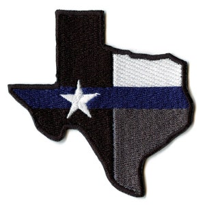 Op de afbeelding: Een geborduurde patch in de vorm van de staat Texas met het ontwerp van de Texas-vlag. De vlag heeft een witte ster op een blauwe streep, een witte streep en een rode streep. De patch is zwart met een dunne blauwe lijn.