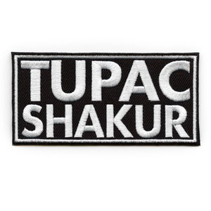 May include: Black and white embroidered patch with the text "TUPAC SHAKUR" in white lettering.