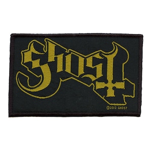May include: A black fabric patch with a gold embroidered logo of the word "Ghost" with a stylised cross. The text "©2012 GHOST" is in the bottom right corner.