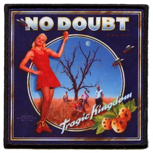 May include: A blue and gold embroidered patch with the text "No Doubt" and "Tragic Kingdom" in a circle. The image features a woman in a red dress holding an orange fruit, a tree, and a group of people in the background.